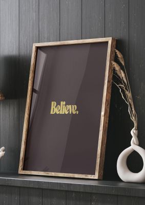 An unframed print of gold inspirational believe quote in typography in brown and black accent colour
